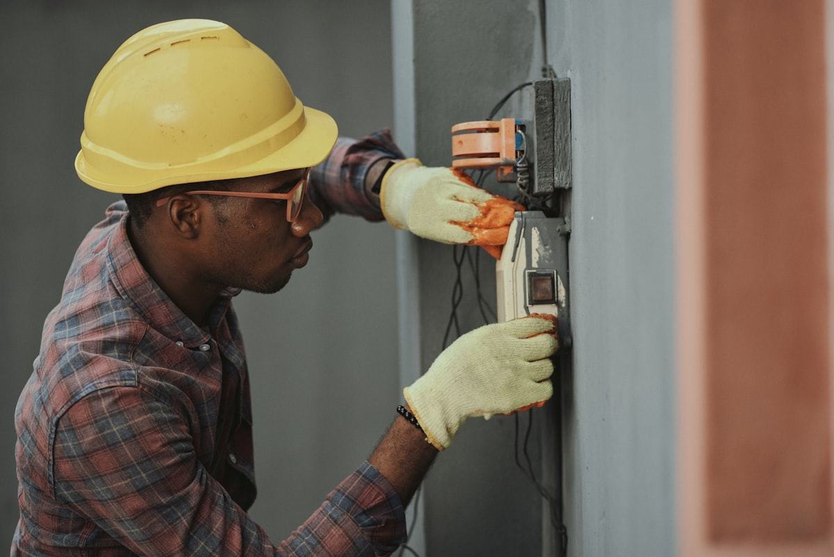 An electrical technician carries out preventive maintenance inside a campus building.